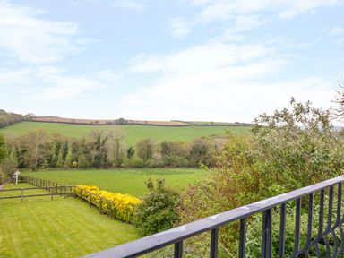 A view of a grassy field and trees with a metal railing in the foreground at Forget-me-not in St Columb Major
