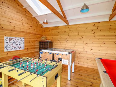 A games room with a foosball table a pool table a pinball machine and wood paneling at Forget-me-not in St Columb Major