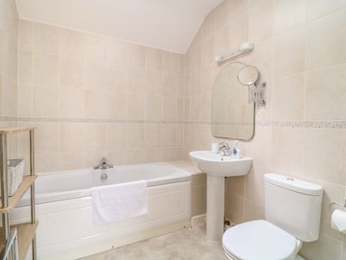 A bathroom with a bathtub a sink with mirror and a toilet at FernGully in St Columb Major