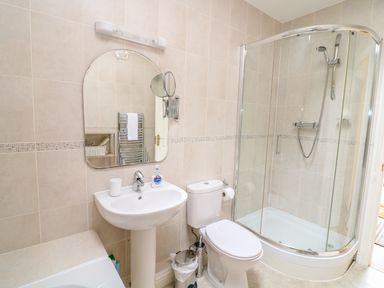A bathroom with a sink a toilet and a glass shower enclosure at FernGully in St Columb Major