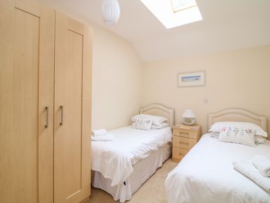 A bedroom with two single beds a wooden wardrobe bedside table and a skylight at FernGully in St Columb Major