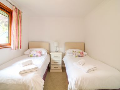 A bedroom with two single beds separated by a nightstand with a lamp at Kingcup Cottage in St Columb Major