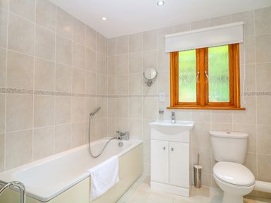 A bathroom with a bathtub sink toilet and a window at Kingcup Cottage in St  Columb Major