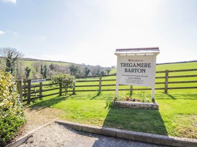 A sign welcoming to Tregamere Barton with a private property gate and green fields in the background