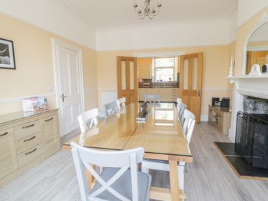 A dining room with table and chairs and a fireplace at Angorfa in Llanbedr