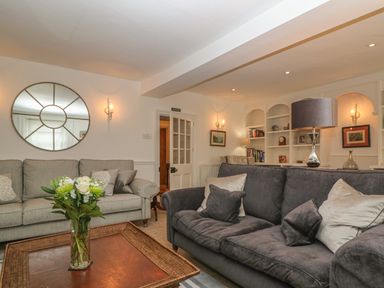 A sitting room with two sofas a mirror on the wall a coffee table with flowers and built in shelves at Dolphin House in Burford