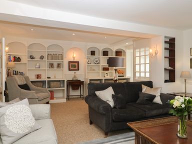 A living room with sofas chairs built in shelves and a wooden coffee table at Dolphin House in Burford