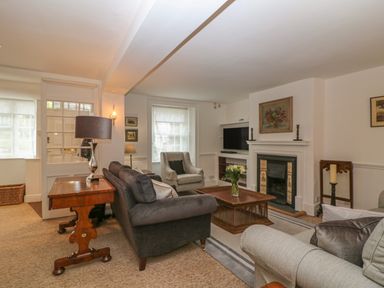 A living room with sofas a coffee table a fireplace and a television at Dolphin House in Burford