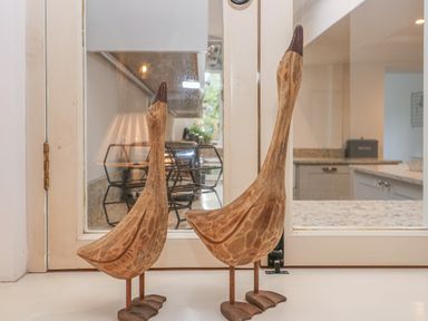 Two wooden duck sculptures on a windowsill with a kitchen visible through the window at Dolphin House in Burford