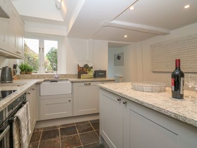 A kitchen with cabinets a sink a wine bottle and glasses on the counter at Dolphin House in Burford