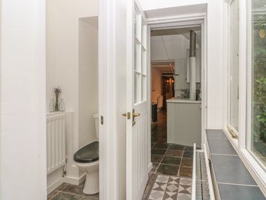 A hallway with a partially open door revealing a small bathroom with a toilet and radiator at Dolphin House in Burford