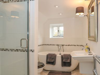 A bathroom with a bathtub a sink a toilet and a shower at Dolphin House in Burford
