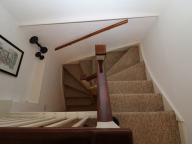A carpeted spiral staircase with wooden handrails and a framed picture on the wall at Dolphin House in Burford