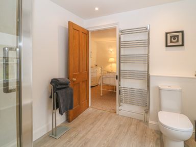 A bathroom with a toilet towel rack and an open door showing a bedroom at Dolphin House in Burford