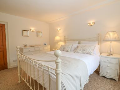 A bedroom with a white metal bed frame two bedside tables with lamps and a dresser with mirrors at Dolphin House in Burford