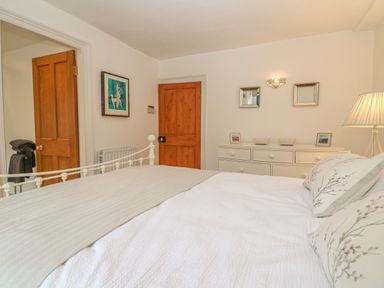 A bedroom with a white metal bed frame two wooden doors and a white dresser with mirrors at Dolphin House in Burford