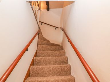 A carpeted staircase with wooden handrails on both sides at Dolphin House in Burford