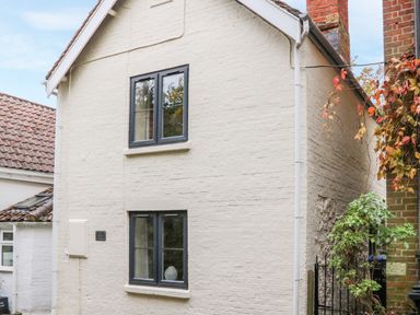 An exterior view of a two-story white brick house with black framed windows and a tiled roof at Tillys Cottage in Edington