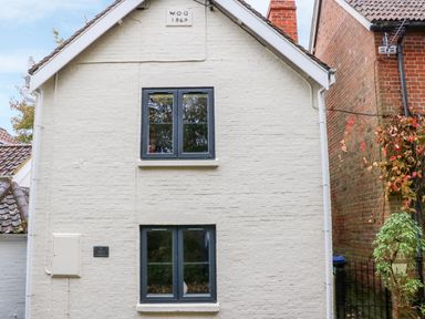 The exterior of a two-story building with white painted brick walls and two windows at Tilly's Cottage in Edington