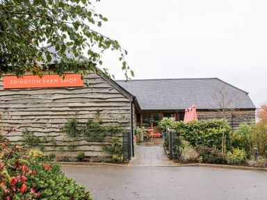 A wooden building with a sign reading Edington Farm Shop and plants around the entrance at Tilly's Cottage in Edington