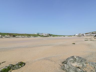 A sandy beach with rocks in the foreground and houses on the hillside in the background at 28 Zenith in Porth