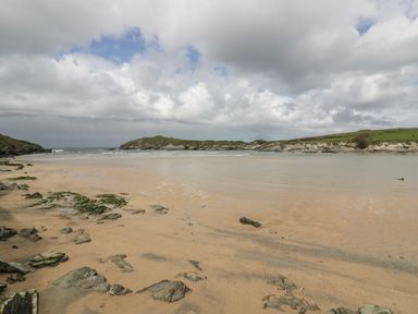 A sandy beach with rocks and a body of water under a cloudy sky at 28 Zenith in Porth