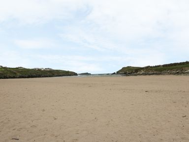 A sandy beach with cliffs on both sides and the sea in the distance at 28 Zenith in Porth