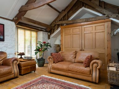 A living room with leather furniture and wooden features at The Meeting House in Ashburton
