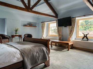 A bedroom with a bed, chairs, and a television at The Meeting House in Ashburton