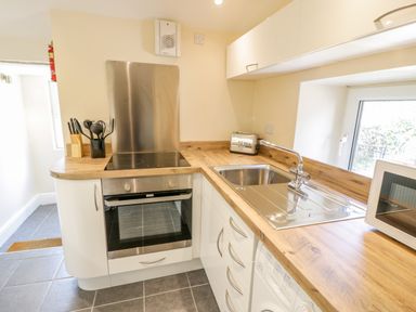 A kitchen with an oven a stovetop a sink toaster microwave and kitchen utensils at Bwthyn Pennant in Porthmadog