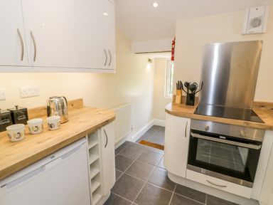A kitchen with white cabinets wooden countertops a stainless steel oven and kettle at Bwthyn Pennant in Porthmadog