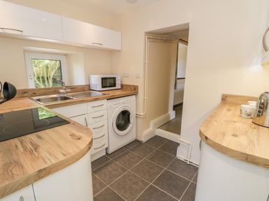 A kitchen with wooden countertops a microwave a washing machine and a sink at Bwthyn Pennant in Porthmadog