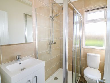 A bathroom with a shower enclosure sink with cabinet toilet and a window at Ash Lodge in Teigngrace near Newton Abbot