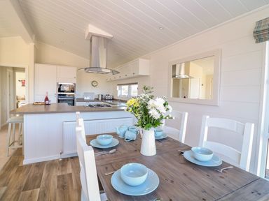 A dining table set with blue bowls and plates and a flower vase in a kitchen at Beech Lodge in Teigngrace near Newton Abbot