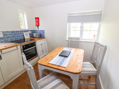 A kitchen with a wooden dining table and four chairs beside a window at Well House Farm Flat 1 in Bretton