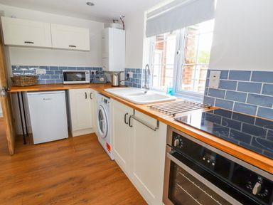 A kitchen with a washing machine refrigerator microwave oven and sink near a window at Well House Farm Flat 1 in Bretton
