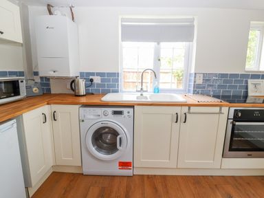 A kitchen with washing machine microwave kettle oven and a sink below a window at Well House Farm Flat 1 in Bretton