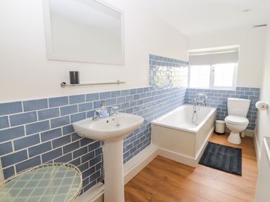 A bathroom with a sink mirror bathtub toilet and a side table at Well House Farm Flat 1 in Bretton