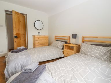 A bedroom with two single beds a wooden dresser a bedside table with a lamp and towels on the beds at Well House Farm Flat 1 in Bretton