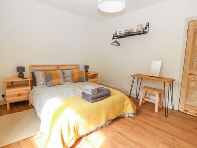 A bedroom with a double bed with pillows and folded towels bedside tables and lamps a wooden dressing table and stool at Well House Farm Flat 1 in Bretton