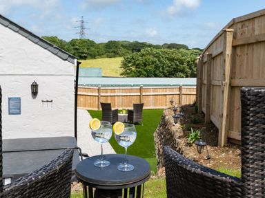 A garden with wicker chairs small table and glasses of water with lemon at Be Our Guest Cottage in Chacewater near Truro