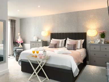 A bedroom with a large bed two bedside tables lamps and a breakfast tray at Be Our Guest Cottage in Chacewater near Truro
