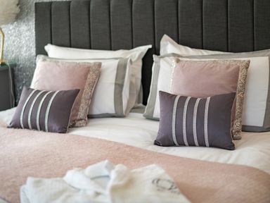 A bed with multiple pillows and a folded robe on top at Be Our Guest Cottage in Chacewater near Truro