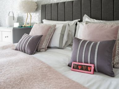 A bed with decorative pillows and a box of chocolates at Be Our Guest Cottage in Chacewater near Truro