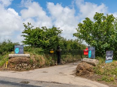 A driveway entrance with stone signs labeled Nantrisack and metal gates surrounded by greenery at Be Our Guest Cottage in Chacewater near Truro