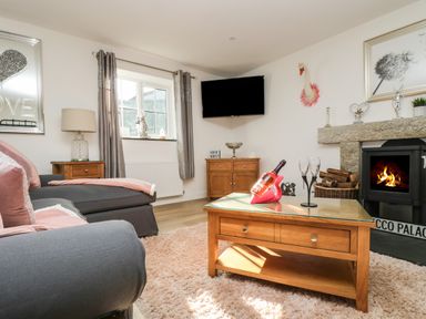 A living room with a grey sofa table lamp fireplace and a wall mounted tv at Be Our Guest Cottage in Chacewater near Truro