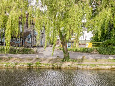 A river with a tree and a stone building behind it at Duck Cottage in Sutton Poyntz
