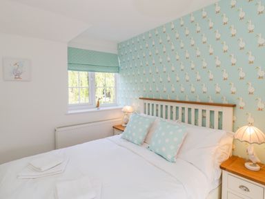 A bedroom with a bed two polka dot pillows duck wallpaper and lamps at Duck Cottage in Sutton Poyntz