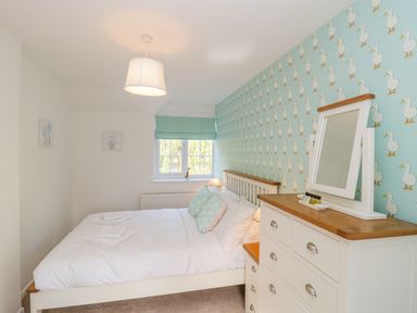 A bedroom with a white bed and duck themed wallpaper at Duck Cottage in Sutton Poyntz