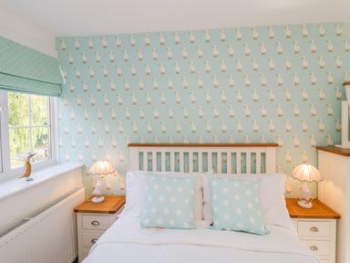 A bedroom with a bed with two polka dot pillows and bedside tables with lamps and duck decorations at Duck Cottage in Sutton Poyntz